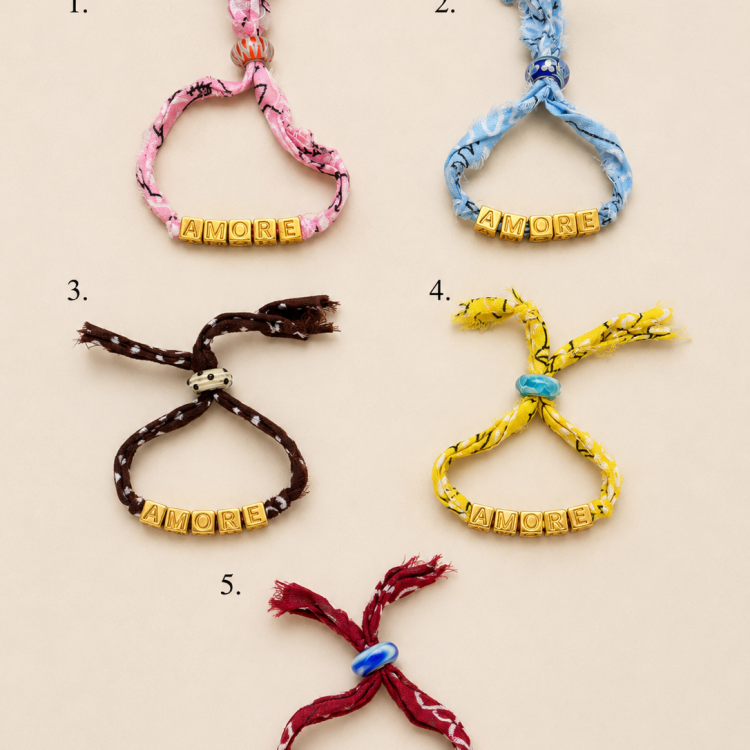 Five fabric bracelets with gold letter beads spelling AMORE, each on a different colored cord (pink, blue, brown, yellow, red).