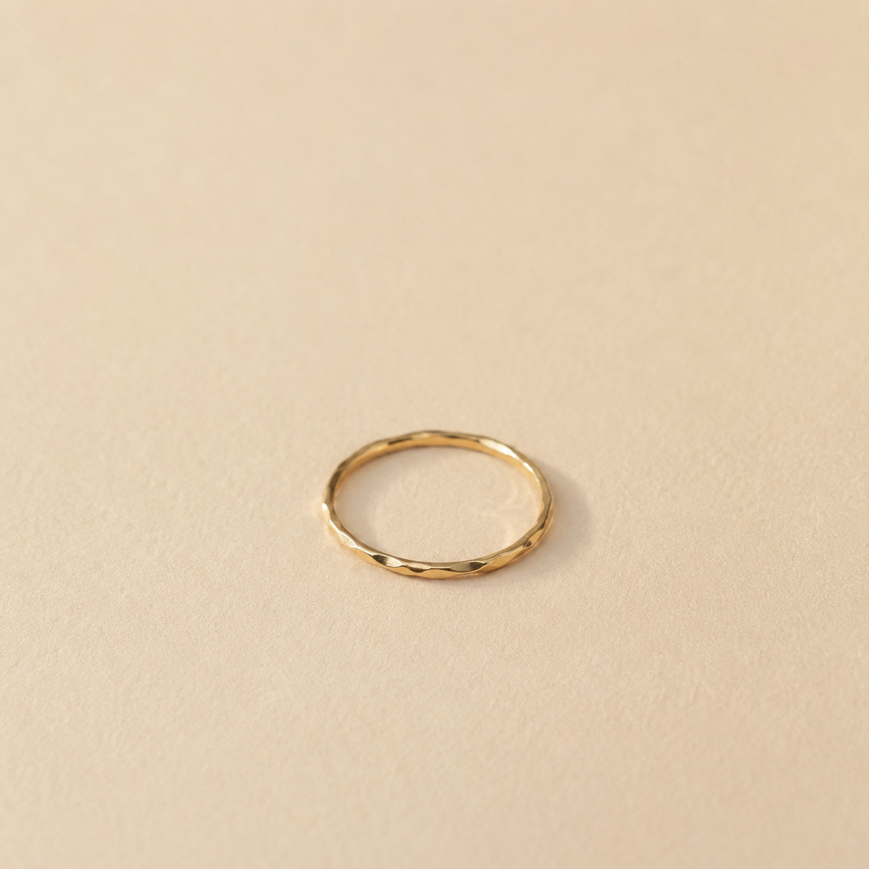 ChatGPT Image 18 mai 2026 12_36_10 | MAISON LIAMA Thin gold band with a faceted texture resting on a beige surface.